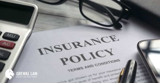 Picture of a document that says "Insurance Policy: Terms and Conditions" with a pen, phone, pair of glasses, and calculator on top.